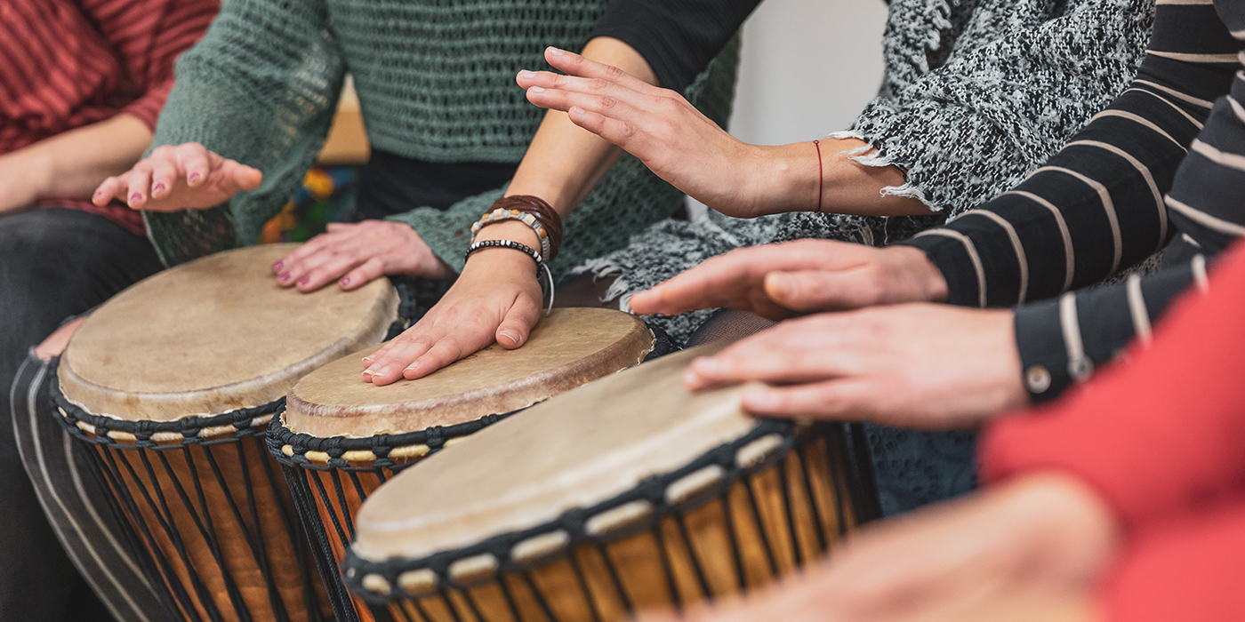 Group of people playing drums during a music therapy lessons, jembe drum, drumming concept