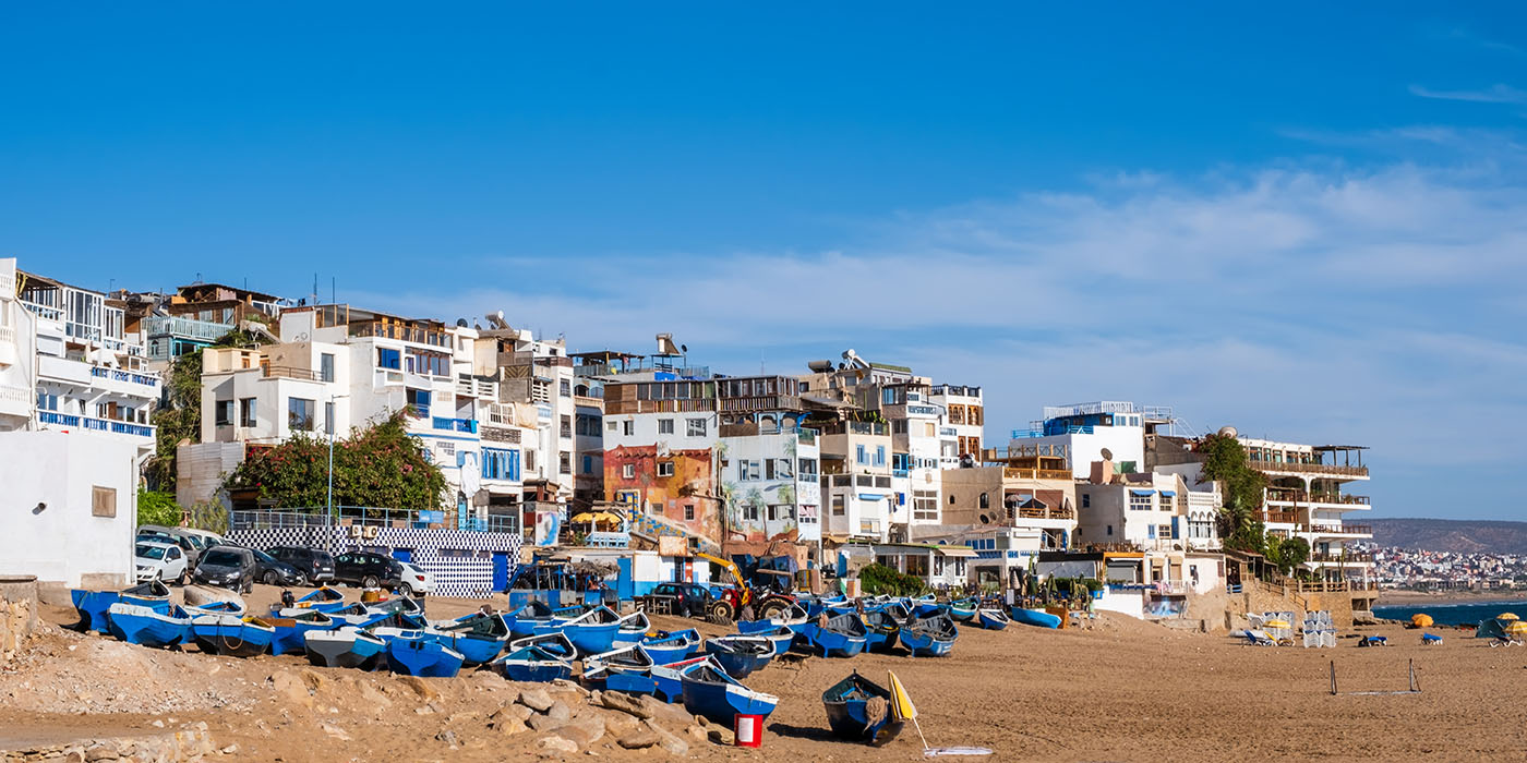 Taghazout, small fishing and surfing village with sandy beach, boats and traditional Moroccan buildings near Agadir, Morocco. Popular seaside resort among surfers